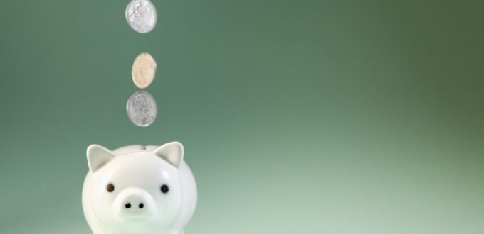 Coins falling into a white piggy bank.